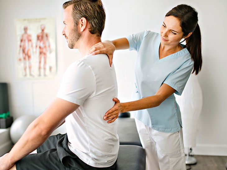 Physiotherapeutin behandelt einen Patienten an der Schulter